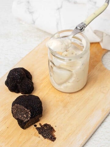 Truffle aioli in a jar with black truffles on a board