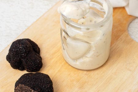Truffle aioli in a jar with black truffles on a board
