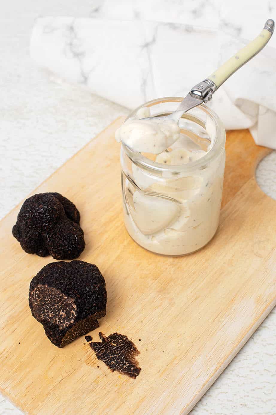 Truffle aioli in a jar with black truffles on a board