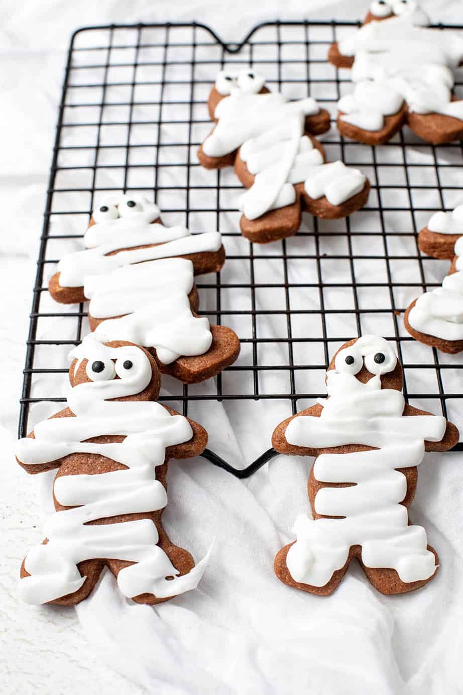 Gingerbread men decorated with icing to ;ook like mummy cookies for Halloween