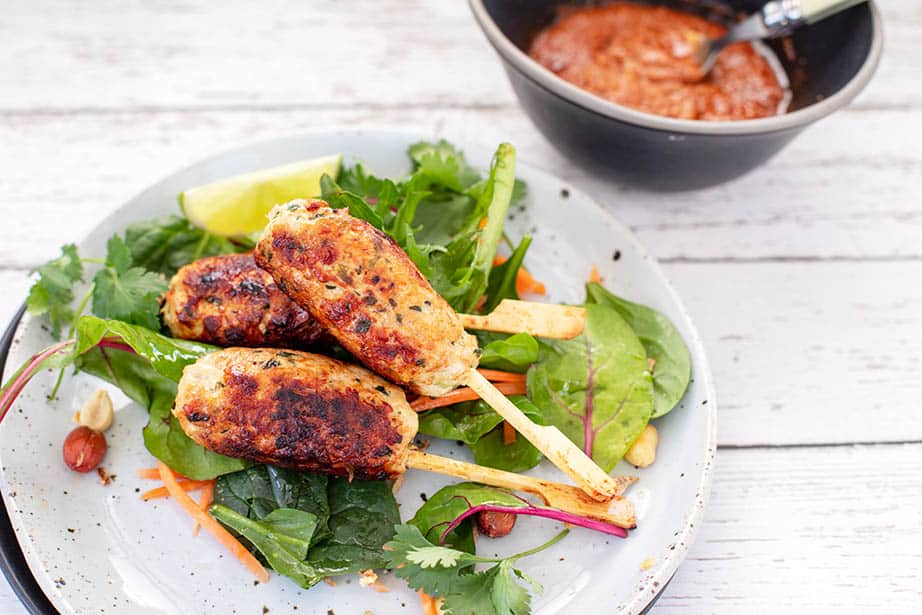 Close up image of Keto chicken kebab served with salad greens and peanut sauce in a bowl on the side