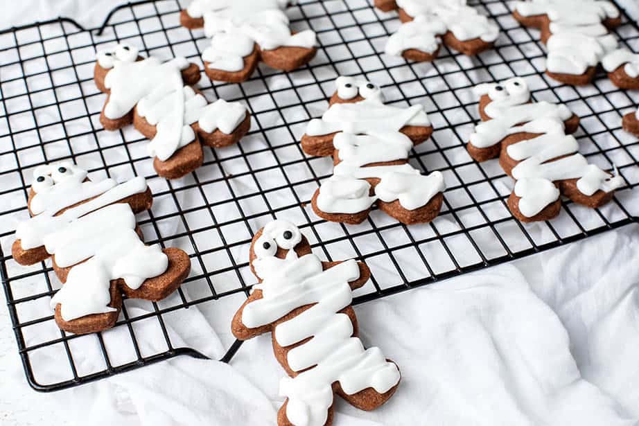 Landscape image of mummy cookies on a cooling tray