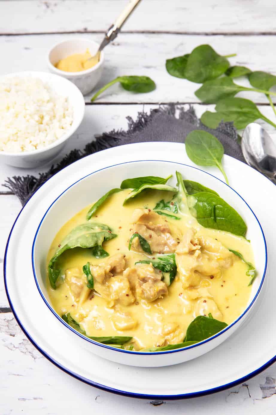 Honey Mustard Chicken in a white bowl with baby spinach