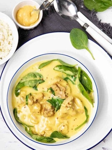 Overhead picture of a white bowl on white wood background and honey mustard chicken