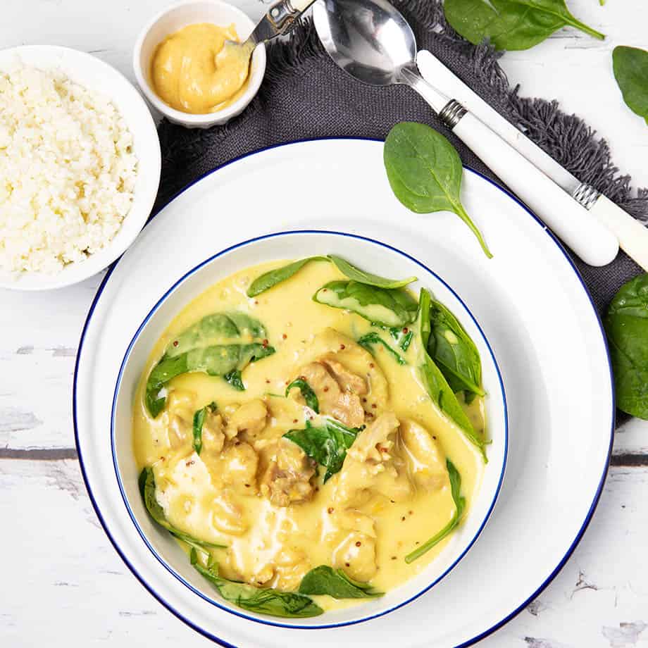 Overhead picture of a white bowl on white wood background and honey mustard chicken