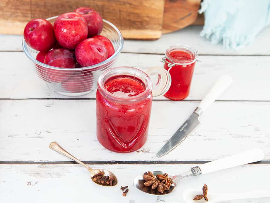 Plum jam on a white wooden background with spices in the foreground