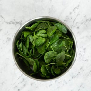 Thermoserver with baby spinach on marble background