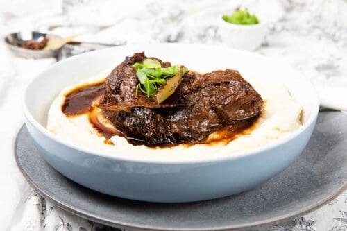 Large bowl of mashed potato covered in slow cooked beef cheeks