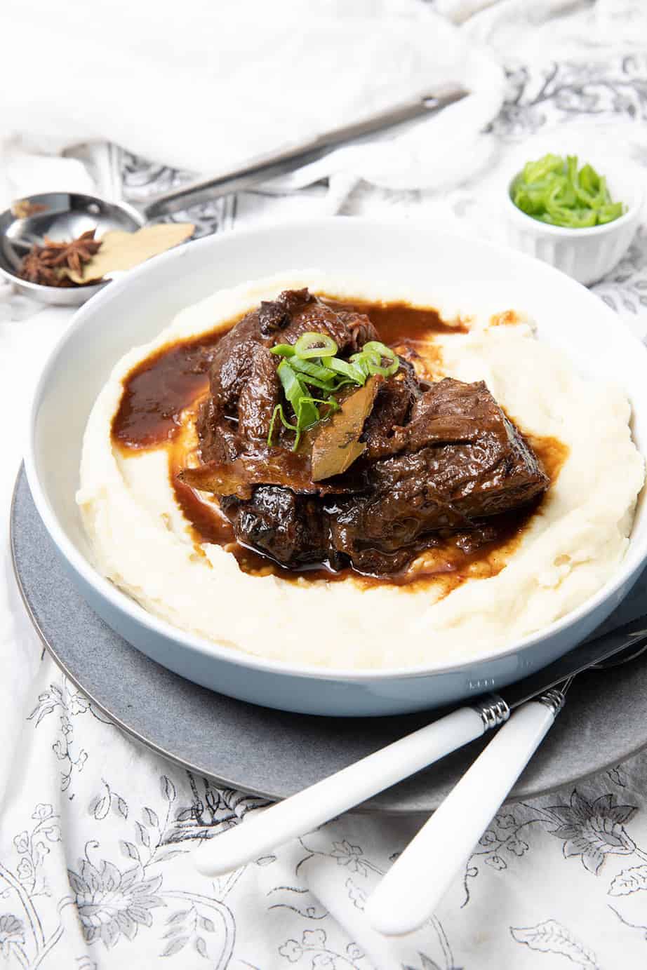 Large bowl of mashed potato with a serving of slow cooked beef cheeks over the top