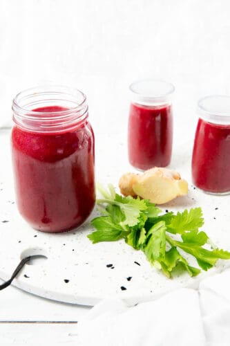 3 glass jars with berry beetroot smoothie on a stone bench.