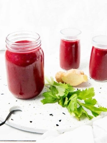 3 glass jars with berry beetroot smoothie on a stone bench.