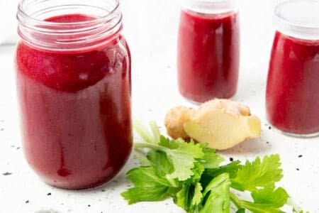 3 glass jars with berry beetroot smoothie on a stone bench.