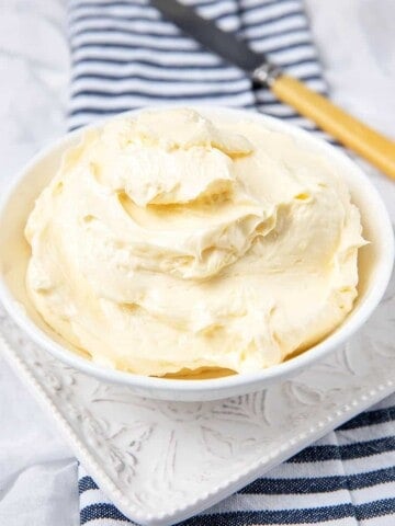 Homemade butter in a white bowl on a white background with a striped napkin