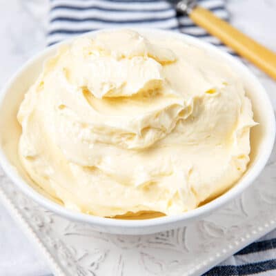 Homemade butter in a white bowl on a white background with a striped napkin