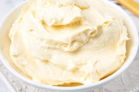 Homemade butter in a white bowl on a white background with a striped napkin