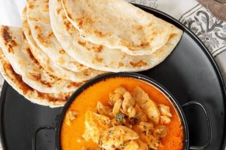 Kashmiri Chicken Curry on a black plate with roti