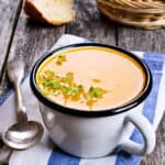 Pumpkin soup in a cup on a wooden background