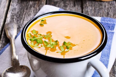 Pumpkin soup in a cup on a wooden background