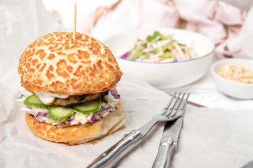 A Thermomix Burger on a white table setting with Thermomix coleslaw.