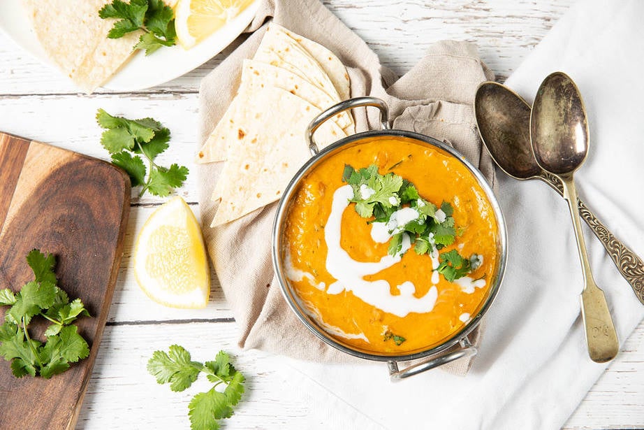 Overhead landscape image of vegan red lentil dahl served with coriander and coconut cream.