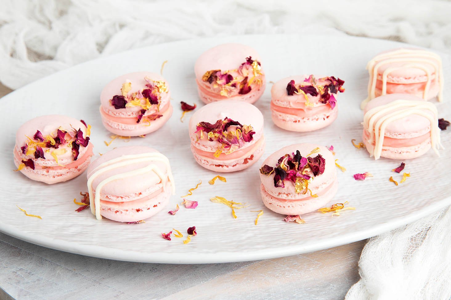 Pink Thermomix macarons on a white plate decorated in rose