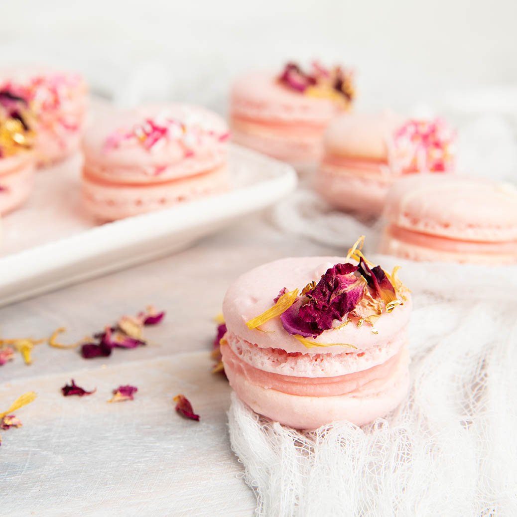 Close up of Pink Thermomix Macaron on a white background with rose petals.