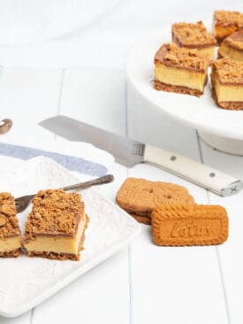 Biscoff Caramel slice on a white serving plate with knife and platter