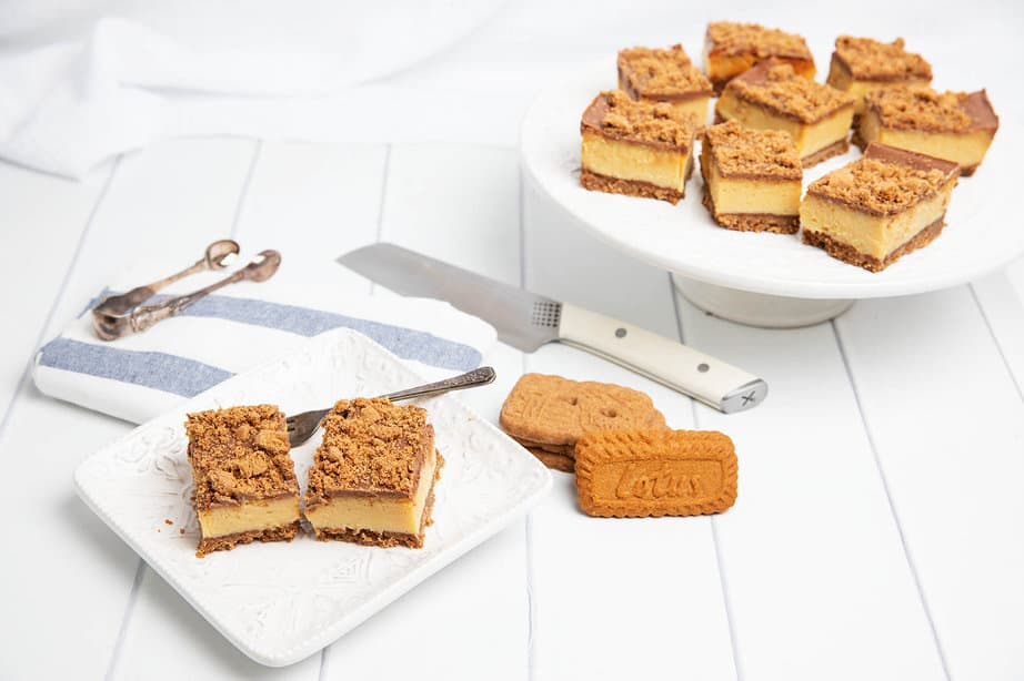 Biscoff Caramel slice on a white serving plate with knife and platter