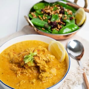 Creamy Moroccan Chicken on white background served with greens