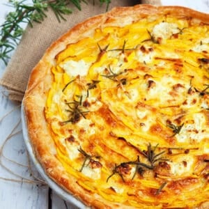 Pumpkin and feta pie on a wooden background with hessian and rosemary.