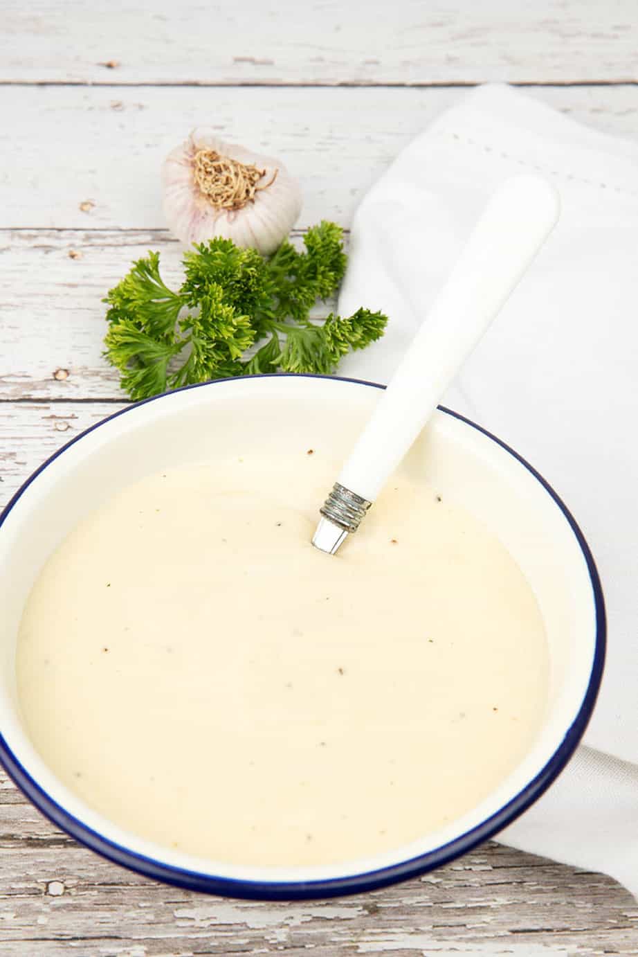 Garlic Sauce in a bowl on a wooden background with a white spoon