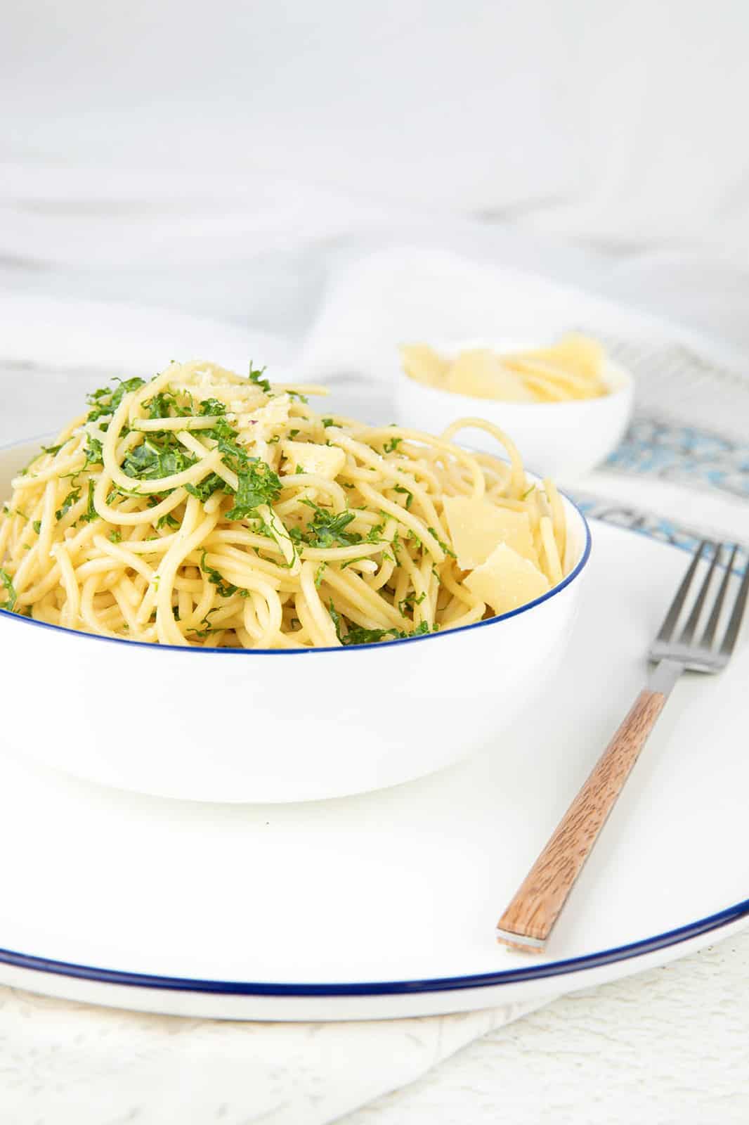 Thermomix Pasta in a white bowl with a fork ready to eat with parsley and cheese