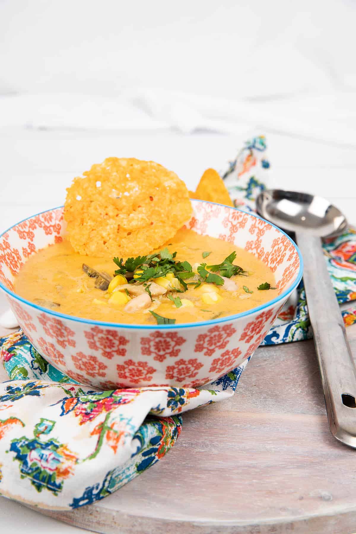 Portrait image single bowl Mexican Chicken soup in a coloured bowl with patterned napkin