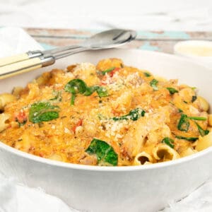 Tuscan chicken in a white bowl served with pasta