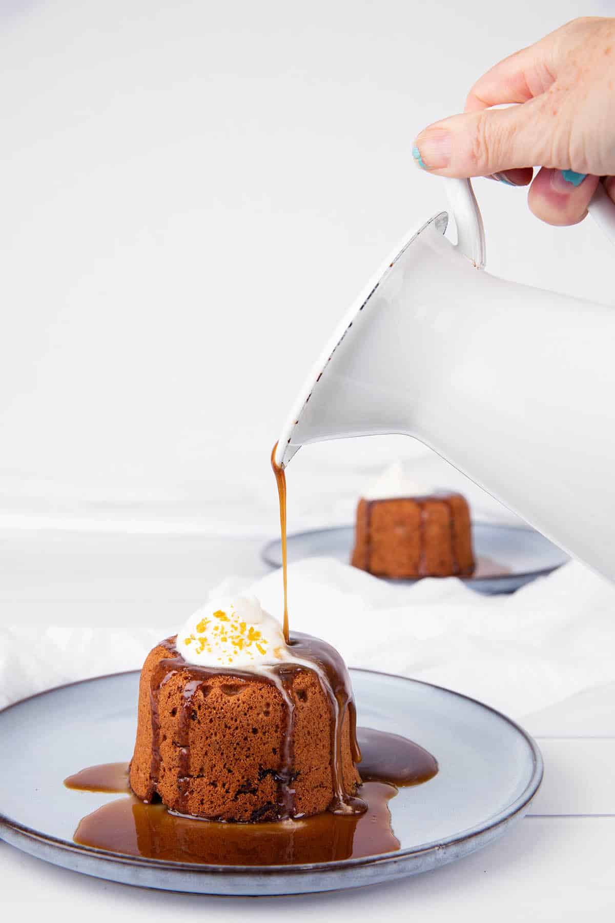 Sticky date pudding Pouring caramel sauce out of a white jug
