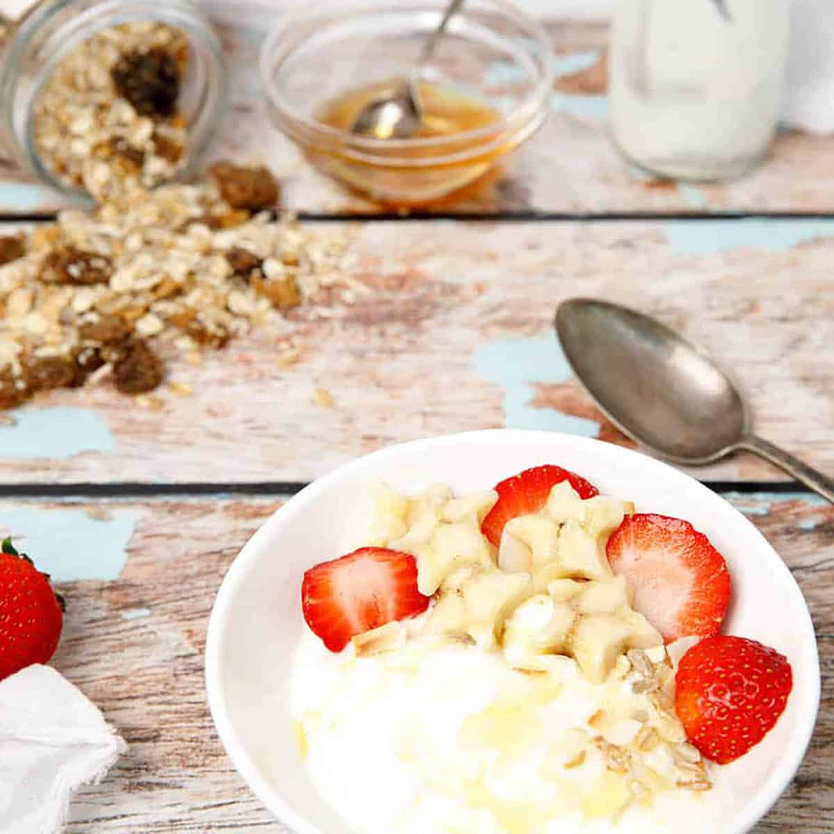 Thermomix Greek Yoghurt on a wooden background with granola and strawberries