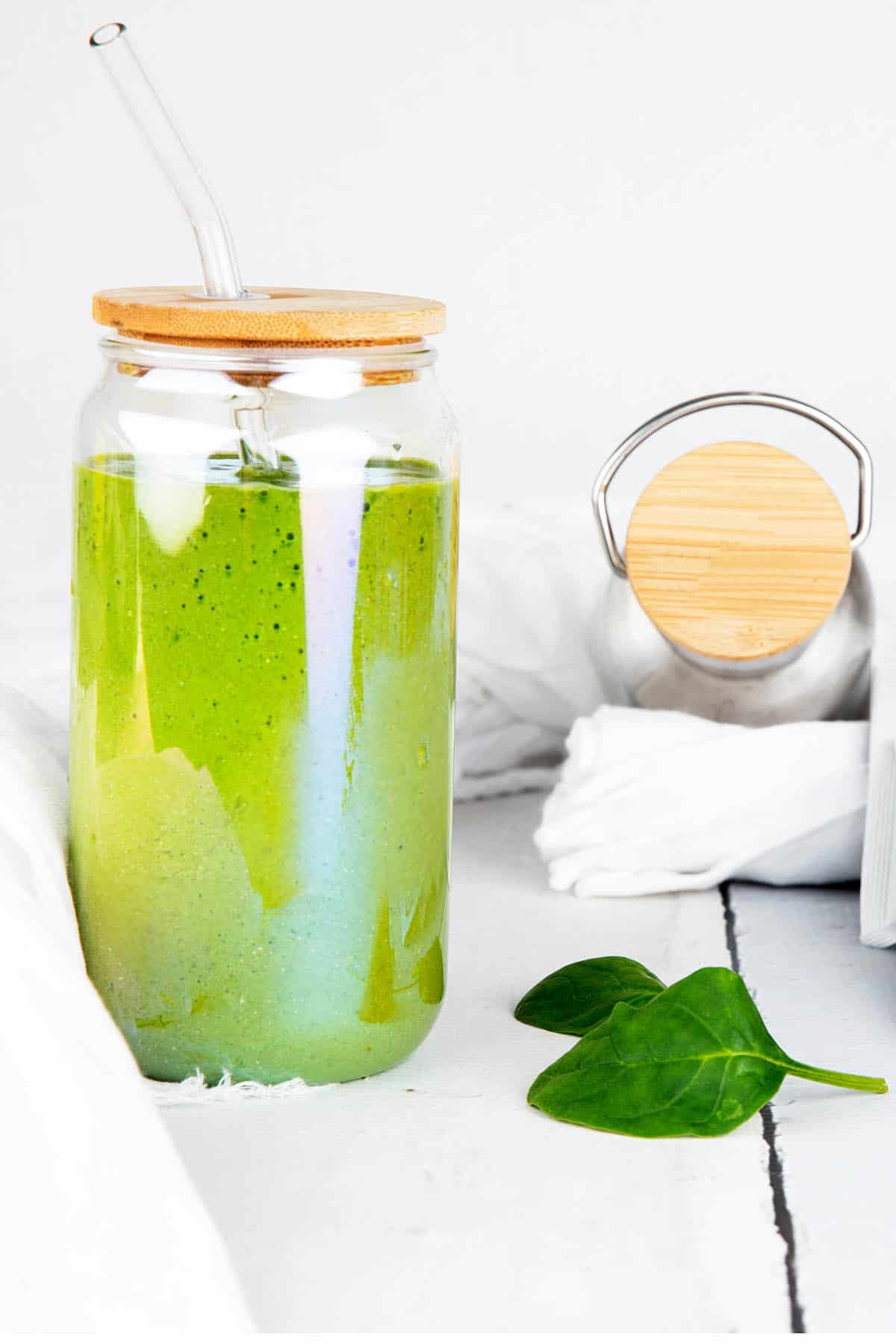 Green Protein Smoothie on a weight background. Spinach leaves and drink bottle.