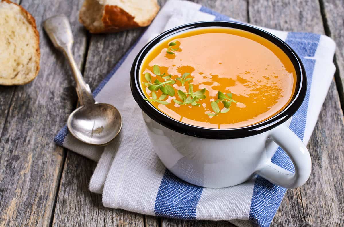 Pumpkin soup in a cup on a wooden background