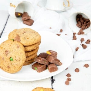 Thermomix Chocolate Chip Cookies on a Cookie sheet on a white background with choc chips scattered everywhere.