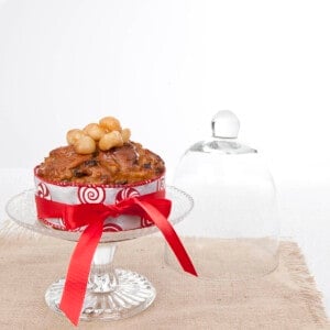 Light Christmas Cake on a glass pedestal with a berlap cloth and white background