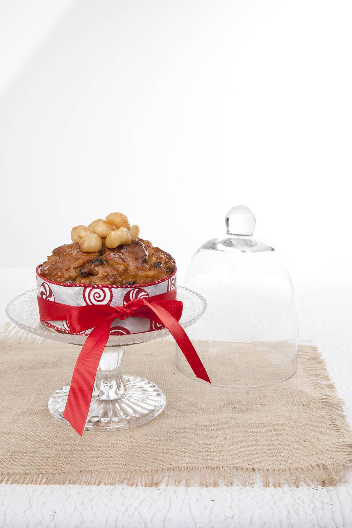 Light Christmas Cake on a glass pedestal with a berlap cloth and white background