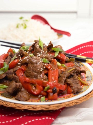 Beef in Black bean sauce on a white background and red napkin. Square Image.