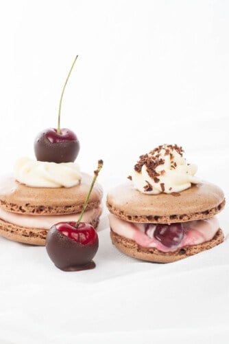 Thermomix Macaron with cream and cherry filling, cherry on top and chocolate on white background