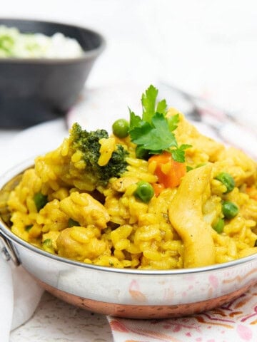 Curried Chicken Risotto on a patterned napkin with a black bowl in the distance