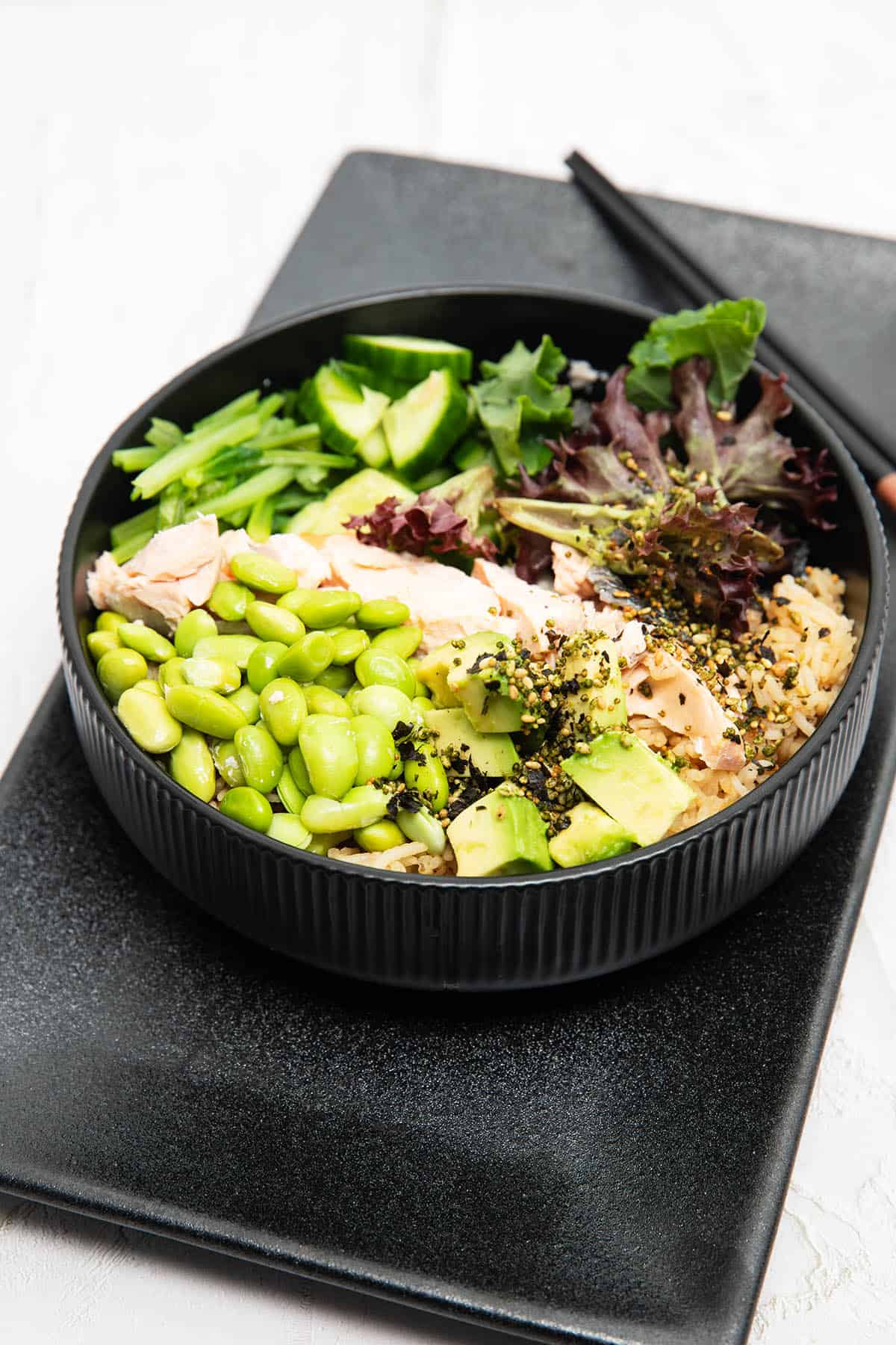 Thermomix Teriyaki Salmon bowl with edamame beans lettuce and advocado sitting on rice in a black bowl.