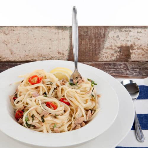 Square image of Tuna liguini with chili and lemon in a white bowl