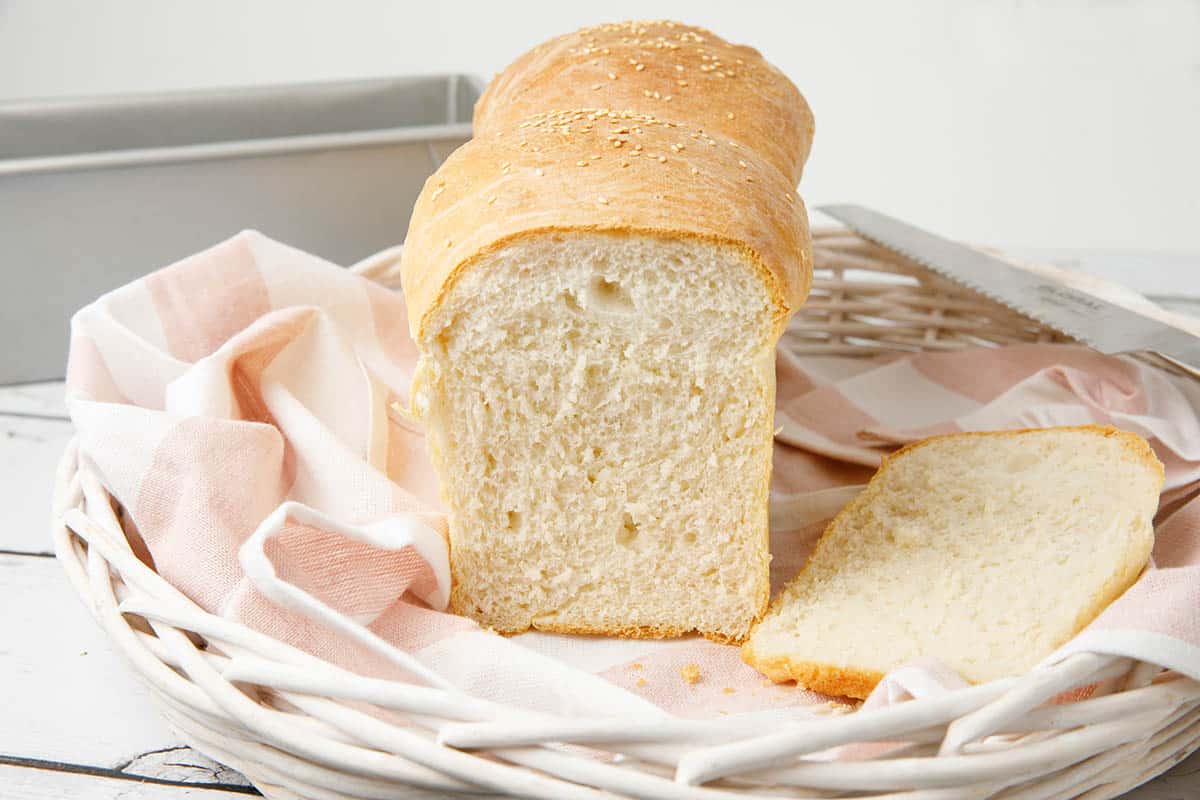 White bread Thermomix in a basket with striped tea towel and bread tin