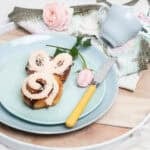 Pink iced cinnamon scroll Easter Bunny made in the Thermomix on a pastel plate background. Potrait image