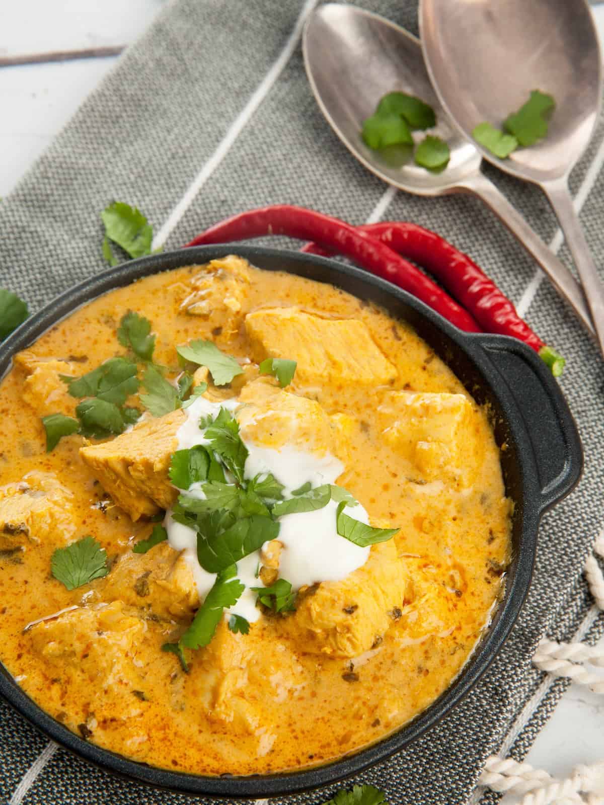 Overhead shot Easy Chicken Curry in black pan with yoghurt and chili