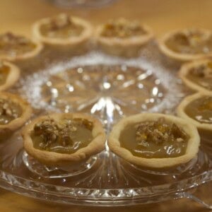 Glass platter of caramel tarts decorated with walnut praline